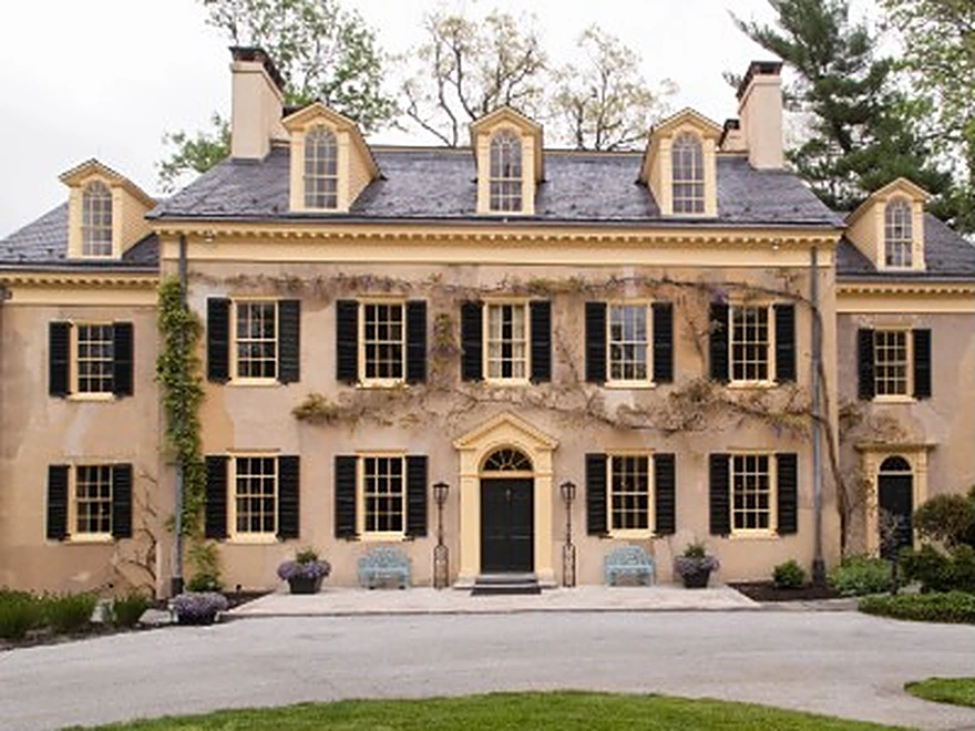 Historic estate exterior, cream stone facade with dark shutters